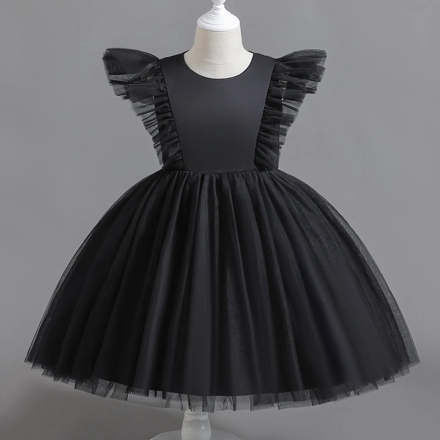 With a charming see-through back, delicate buttons, and playful tulle skirt and sleeves, it's the perfect blend of elegance and childhood magic.